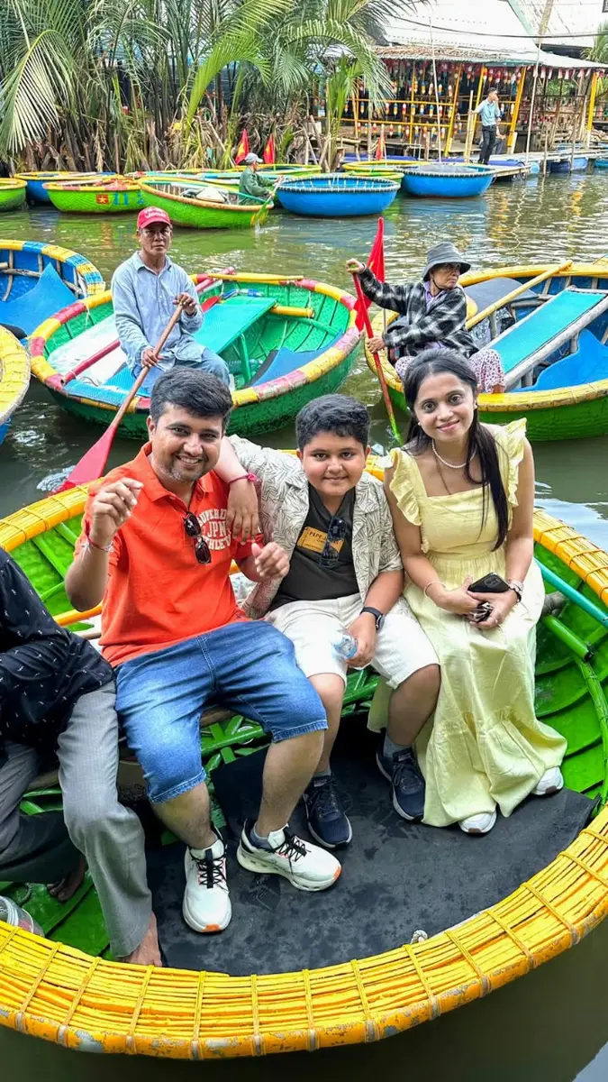 A family of three sitting together in a painted basket boat at the coconut village in Hoi An, Vietnam