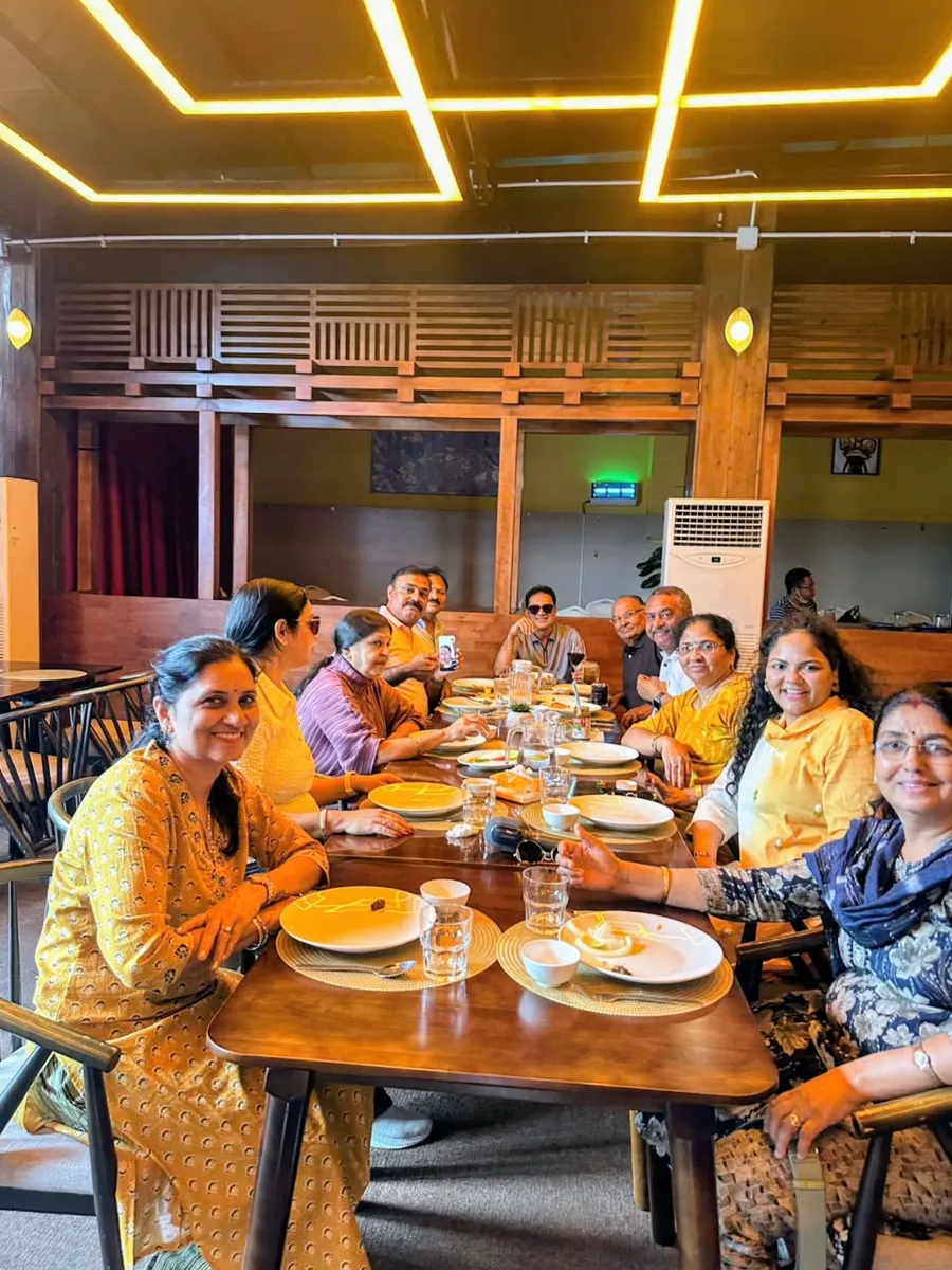 A travelling party seated along one long table at dinner in a warmly lit restaurant in Vietnam