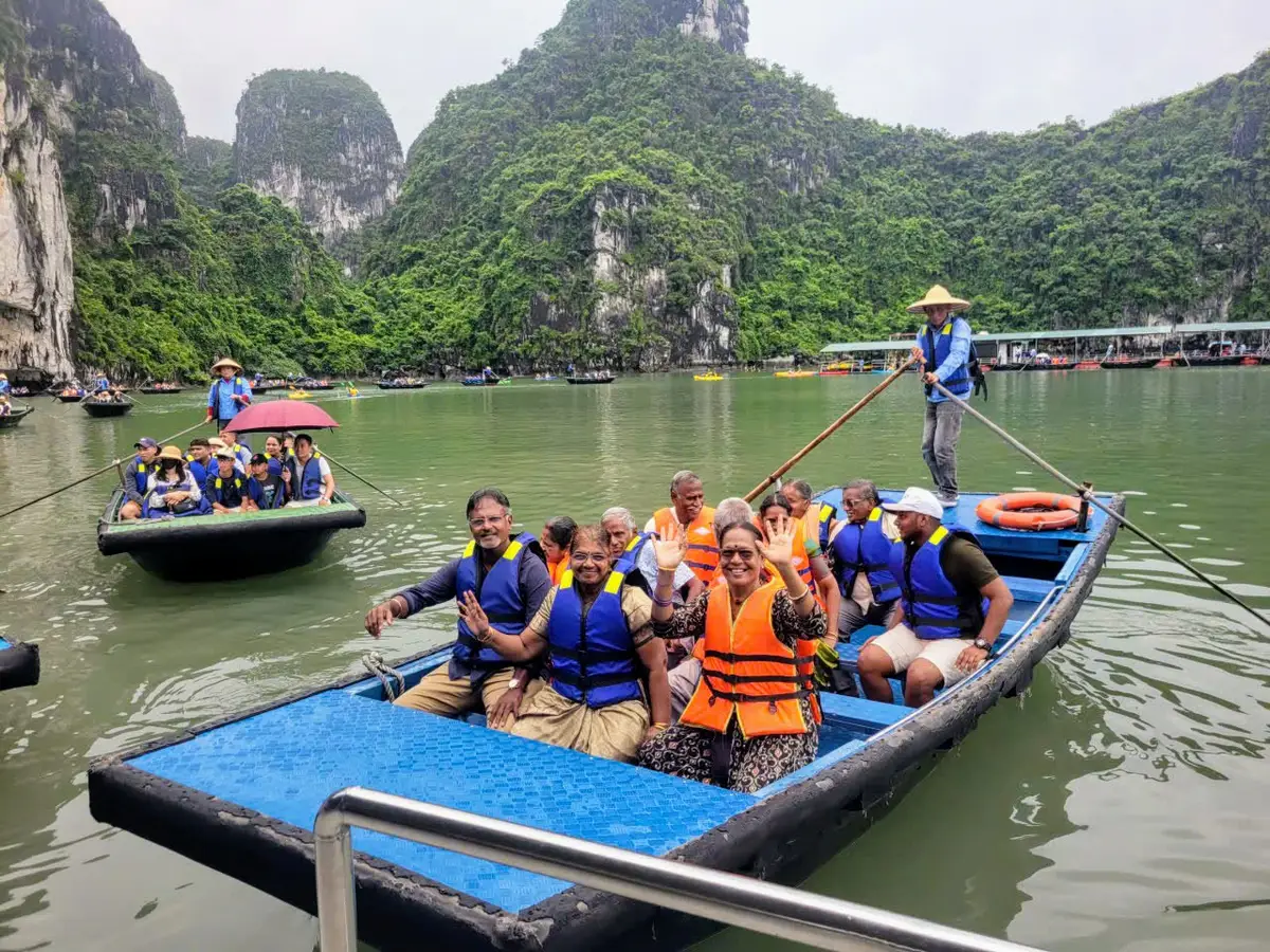 Travellers in life jackets aboard a rowing boat among the limestone karsts of Halong Bay, Vietnam