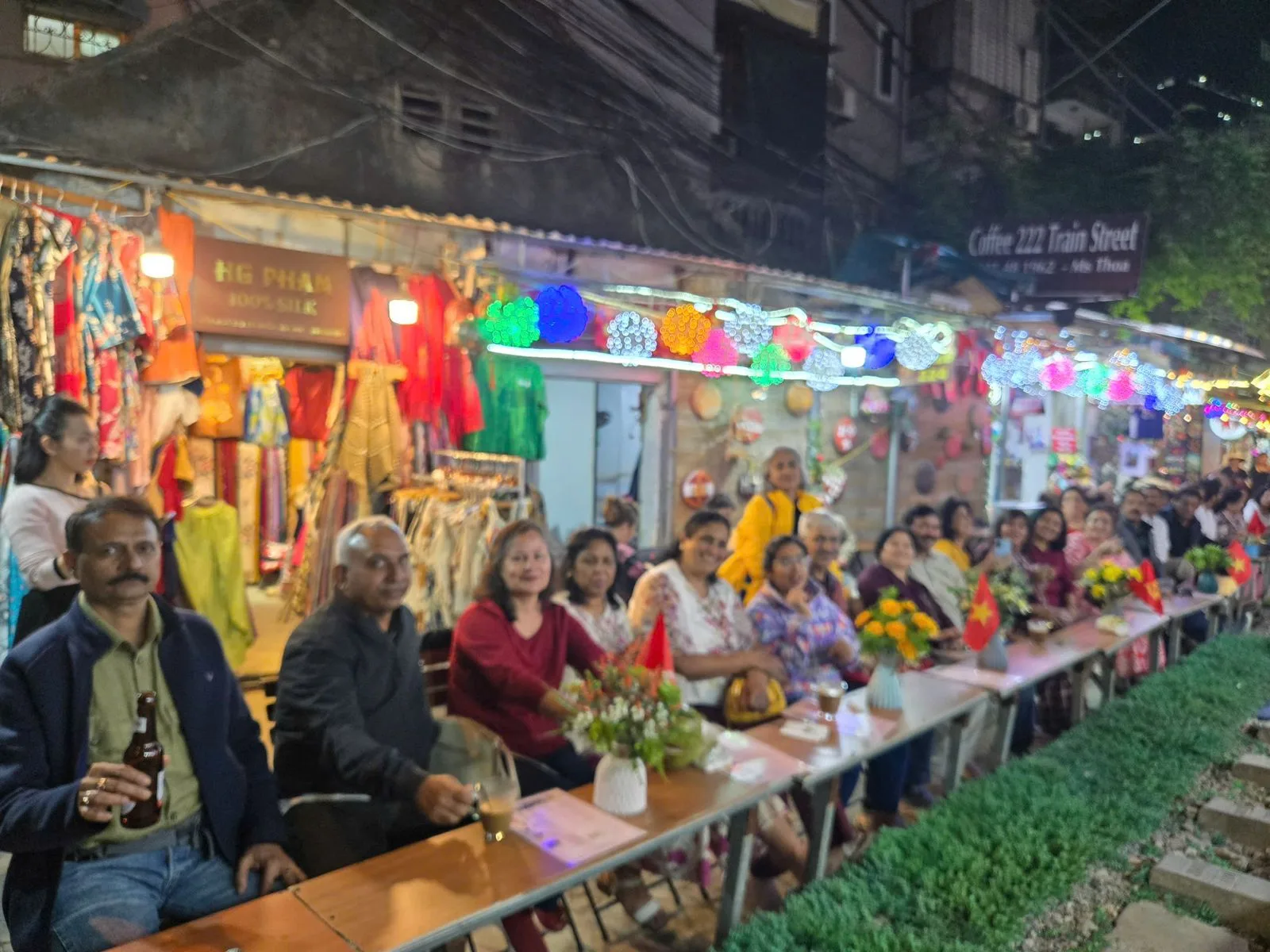 A large travel group at a long table dinner on Hanoi's Train Street