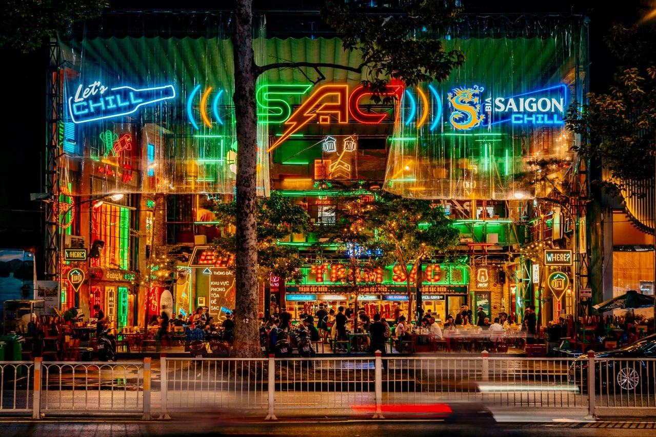 A neon-lit rooftop bar street scene in Ho Chi Minh City